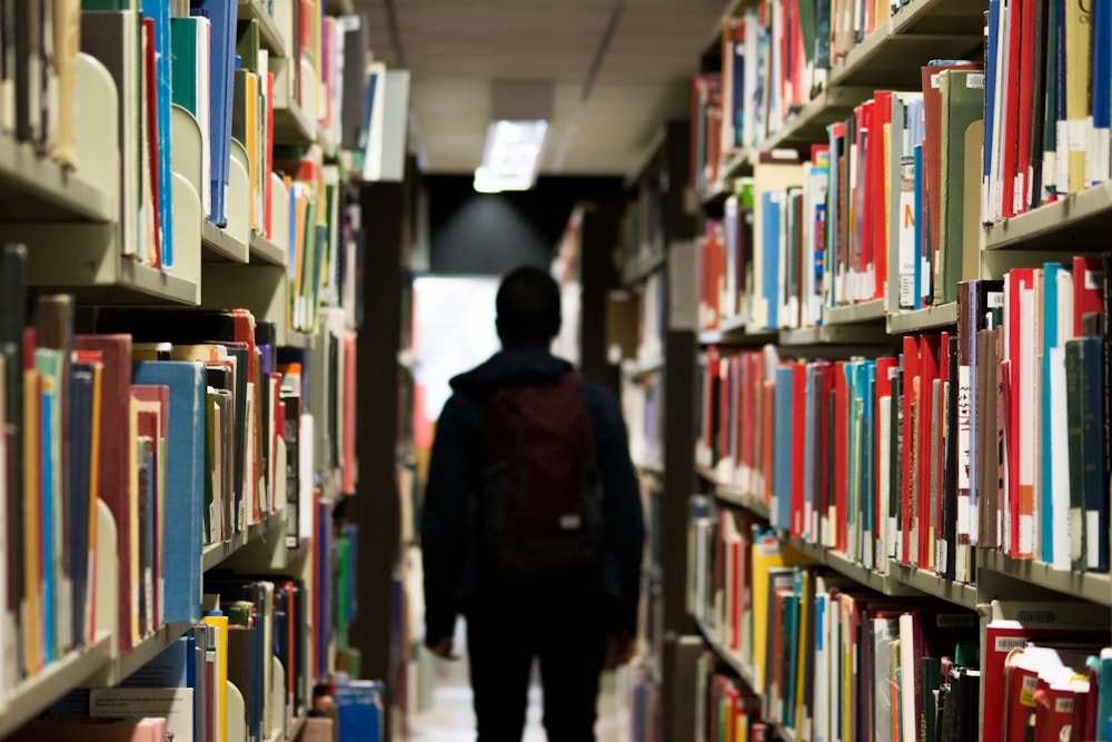 A student walking through library bookshelves